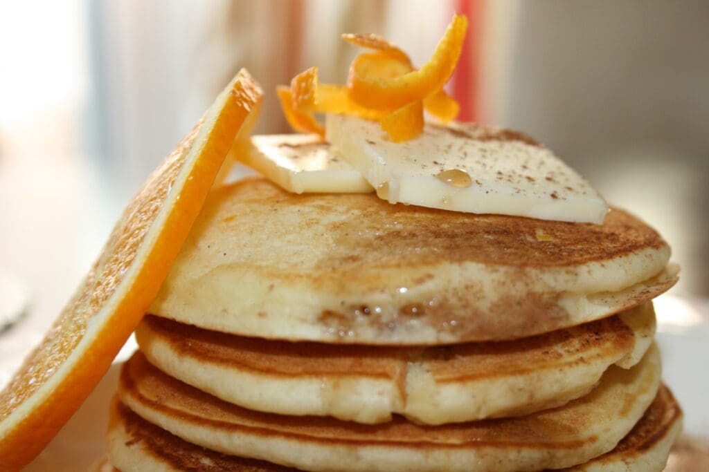 A stack of orange pancakes on a plate.