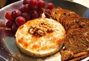 A plate with cheese, grapes, and walnuts is a delicious and elegant dish to serve at any gathering.