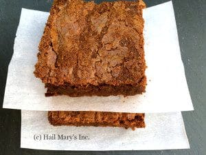 Two squares of chocolate brownies on a napkin.