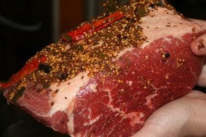 A person holding a piece of meat with spices on it.
