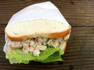 On a wooden table, there is a delicious chicken salad sandwich.