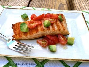 Grilled salmon with avocado on a plate.