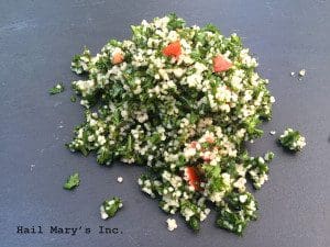 A pile of couscous on a black plate, perfect for a tabbouleh recipe.