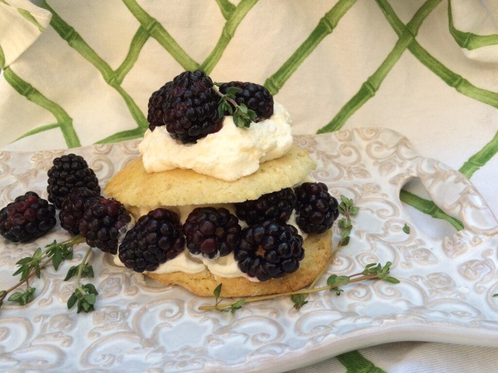 Delicious blackberry biscuits topped with whipped cream and thyme, perfect for summer desserts.