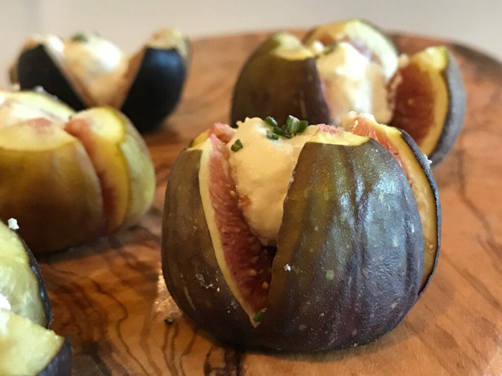 Figs stuffed with goat cheese on a wooden cutting board, drizzled with balsamic glaze.