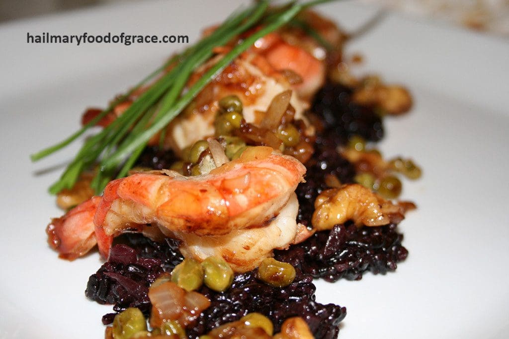 A plate with shrimp and black rice on it.