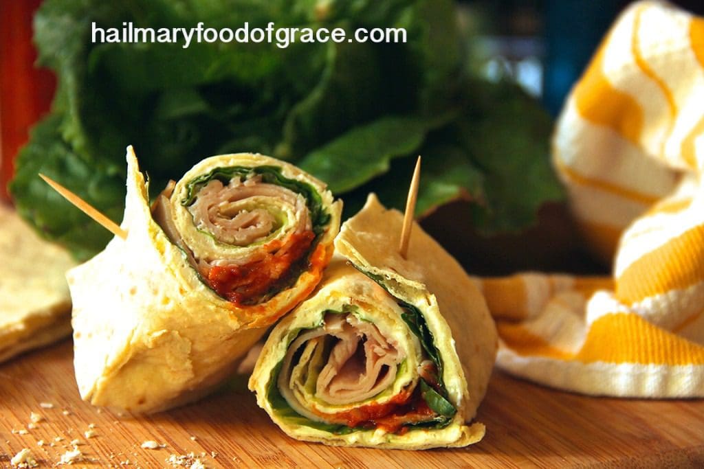 A wrap with meat and vegetables on a cutting board.