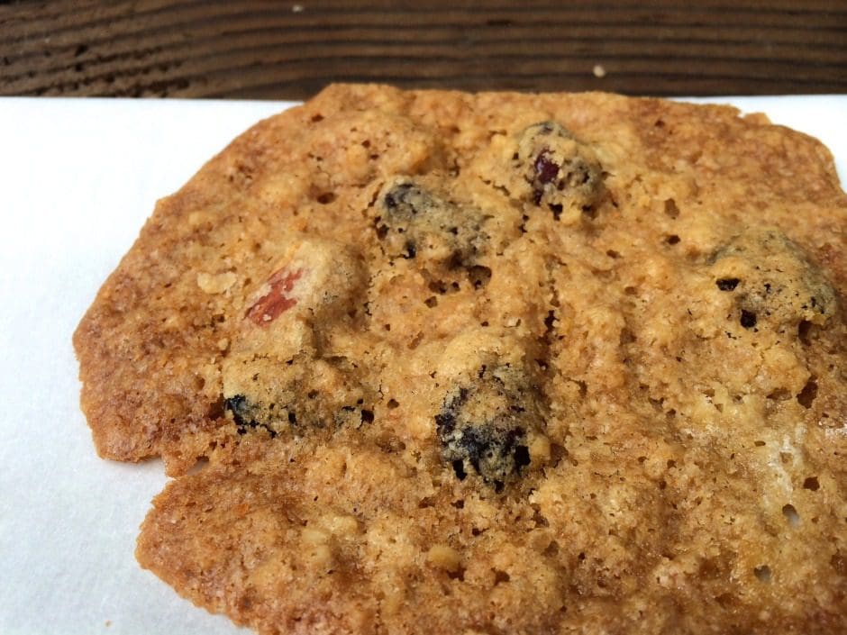 A cookie with raisins on top of a napkin.