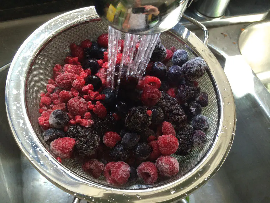 Berries are being poured into a bowl of water.