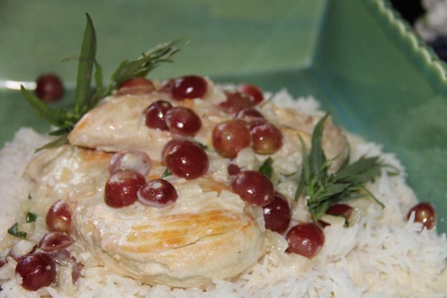 Chicken with grapes and rice in a green bowl.