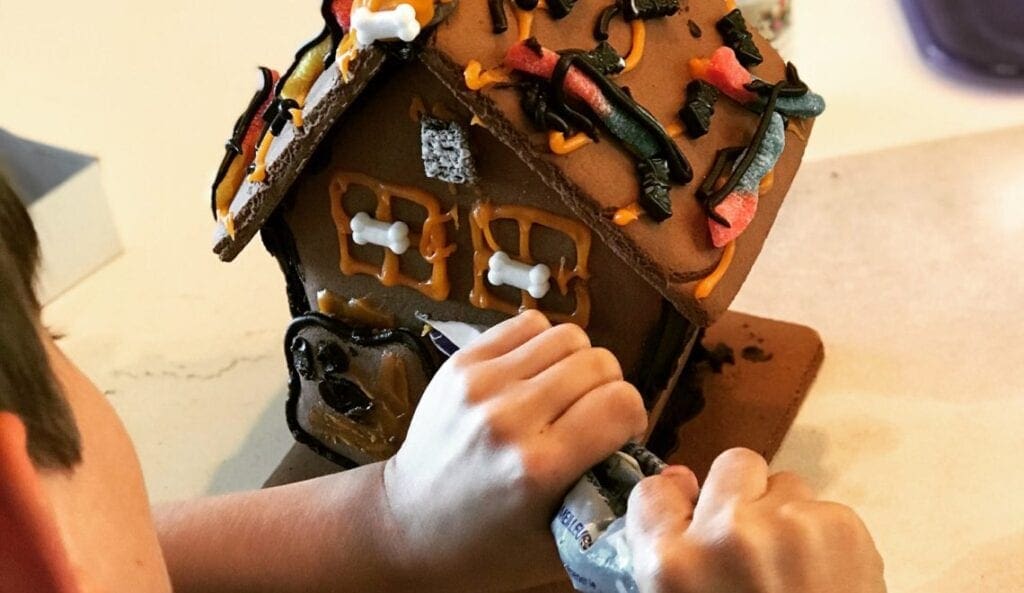 A child is decorating a gingerbread house.