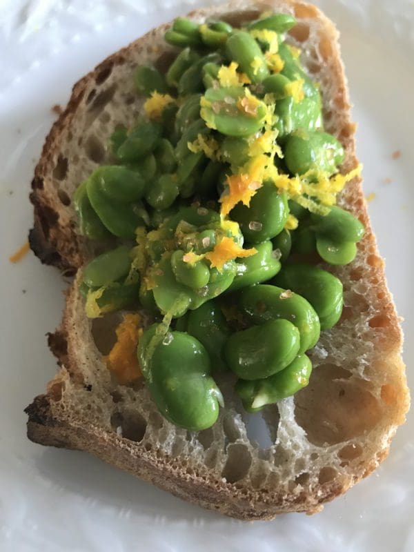 A piece of bread with green beans on it.