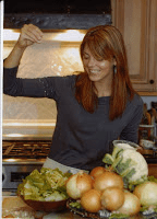 A woman standing in front of a kitchen full of vegetables.