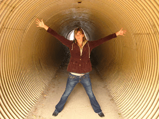 A woman standing in a tunnel with her arms outstretched.