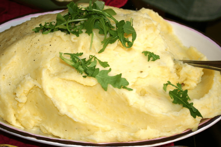 A plate of mashed potatoes with a fork.