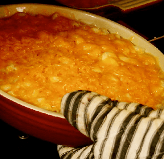 A person holding a dish of macaroni and cheese.
