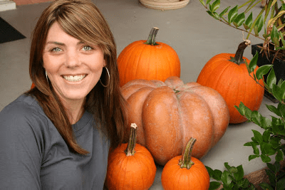 A woman sitting on a porch with pumpkins.