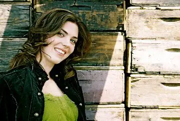 A woman smiling in front of wooden crates.