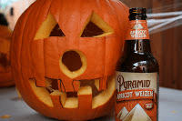 A pumpkin with a bottle of beer next to it.