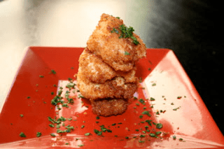 A stack of chicken nuggets on a red plate.