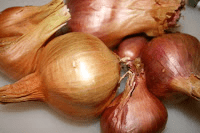 A pile of brown onions on a cutting board.