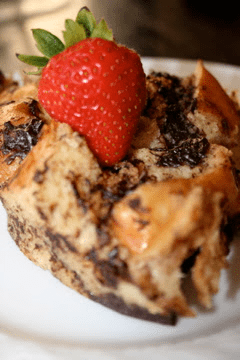 A piece of chocolate bread with a strawberry on top.