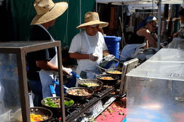 A group of people preparing food at an outdoor market.