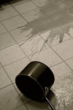 A black and white photo of a black pot on a tiled floor.