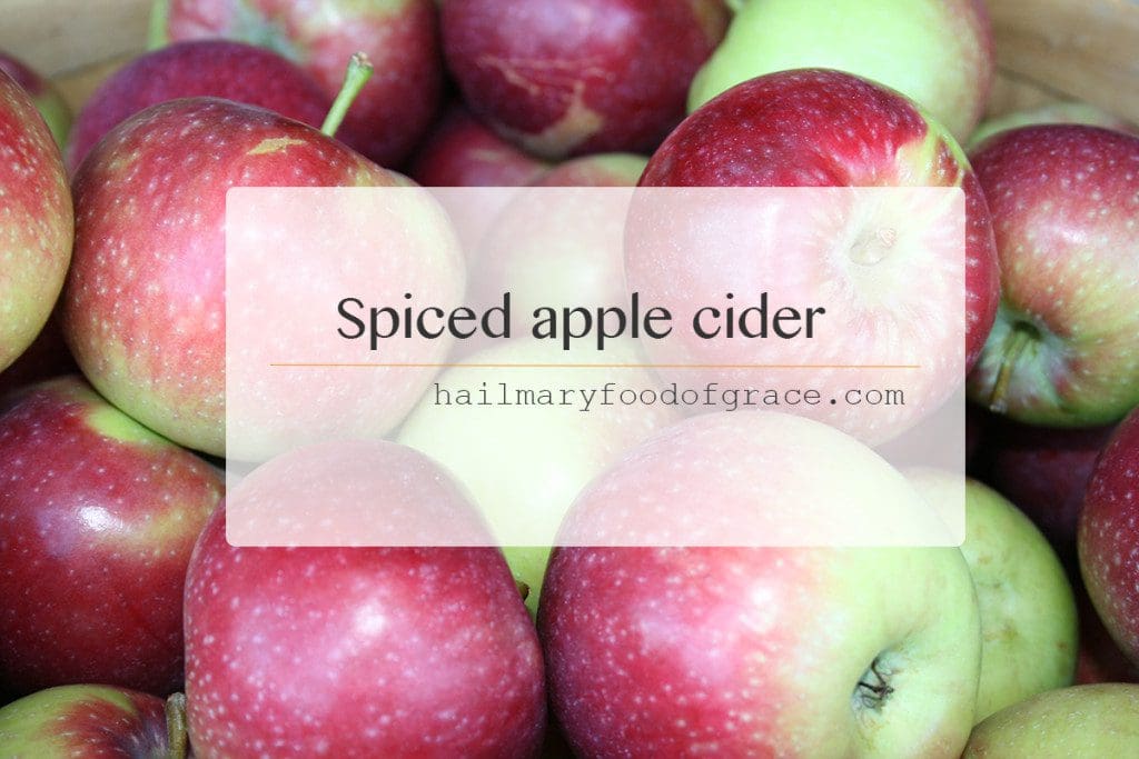A bowl of apples with the words spiced apple cider.