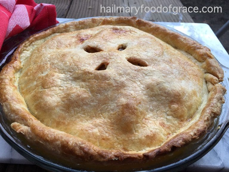 A pie is sitting on a table next to a red napkin.