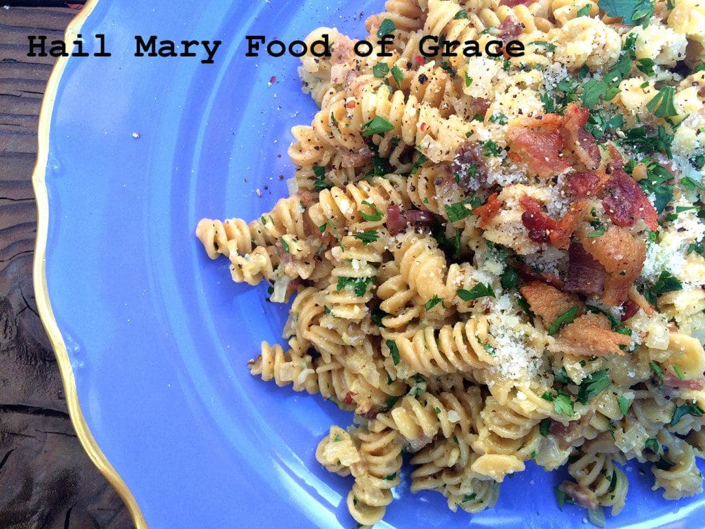 A blue plate with pasta and bacon on it.