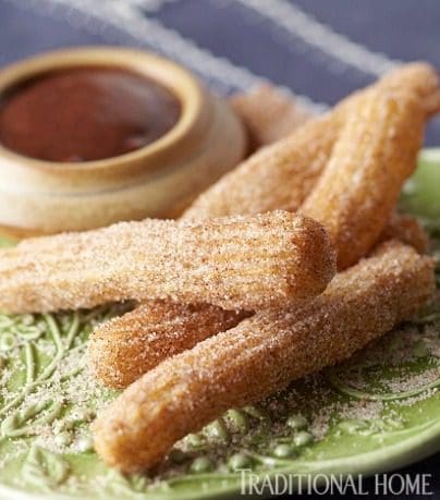 Traditional churros on a plate with dipping sauce.