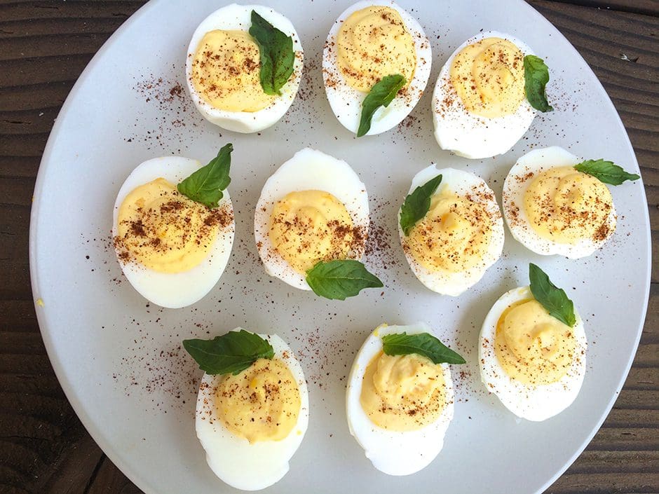 Deviled eggs on a plate with mint leaves.