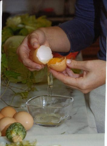 A person is preparing an egg in a kitchen.