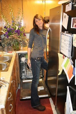 A woman standing in front of a dishwasher.