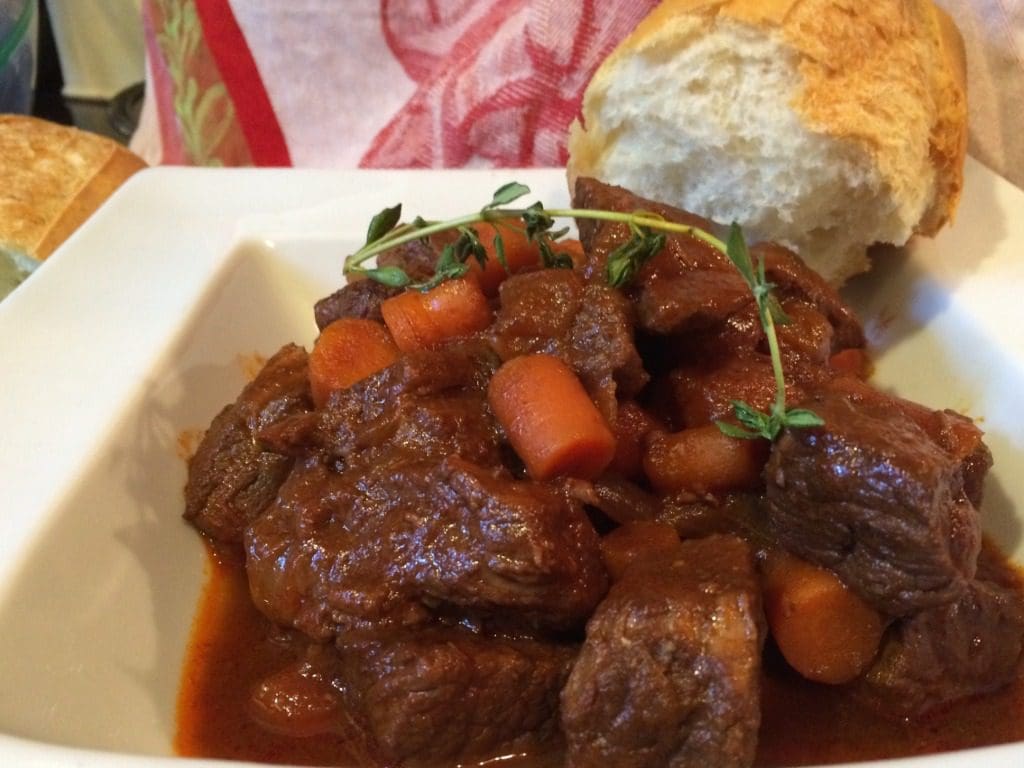 Beef stew with carrots and bread on a plate.