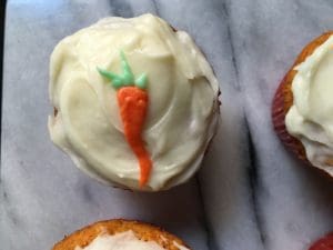 Carrot cupcakes with icing and carrots.