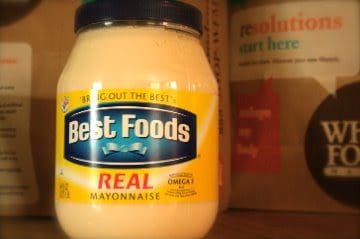 A jar of best foods real hummus sitting on a shelf.