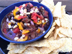 A bowl of black bean and corn salsa on a plate with tortilla chips.