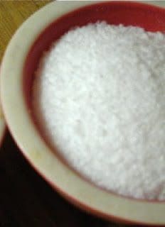 Two bowls of white salt on a wooden table.