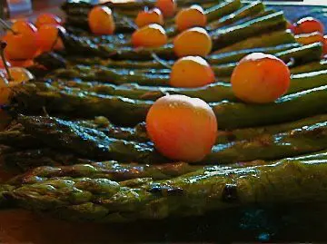 A plate with asparagus and cherries on it.