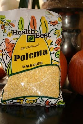 A bag of polenta sitting on a table next to pumpkins.