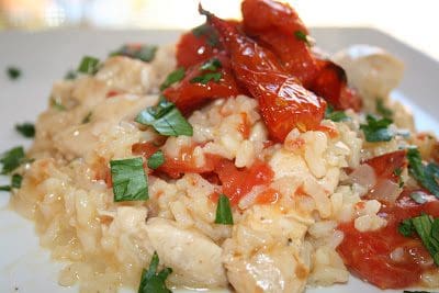 Risotto with chicken and tomatoes on a white plate.