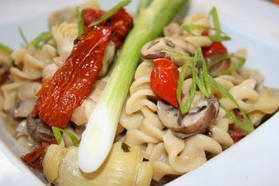 A plate of pasta with mushrooms and leeks on it.