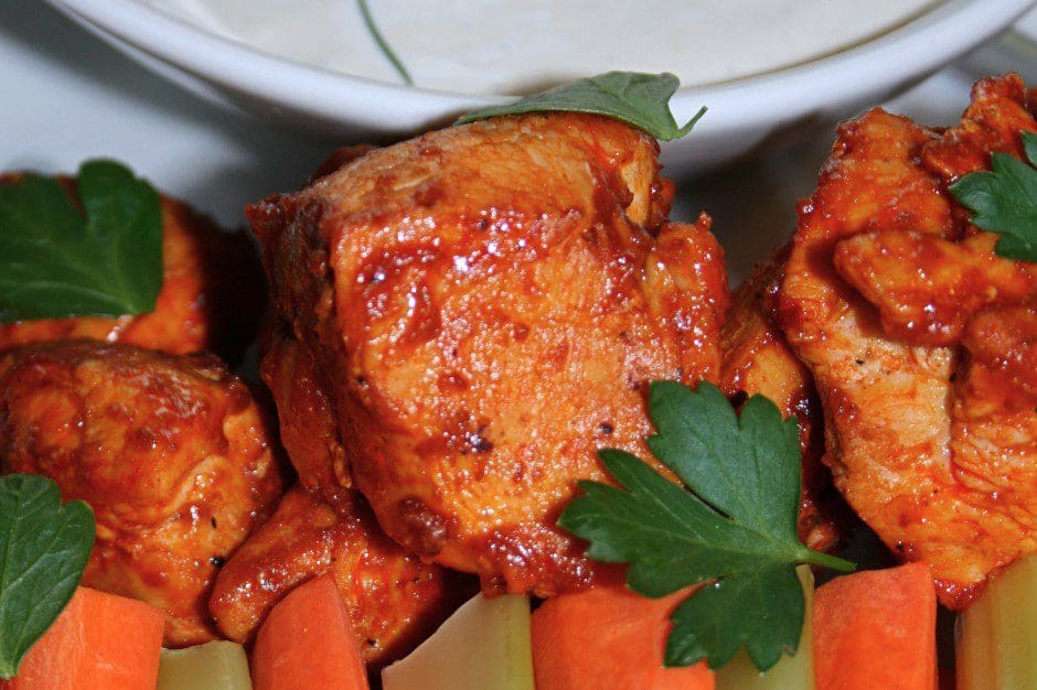 A plate with chicken skewers, carrots and dip.