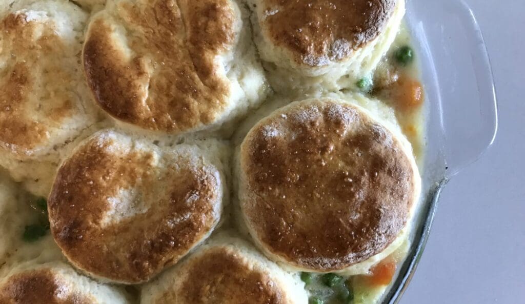 A casserole dish filled with biscuits and peas.