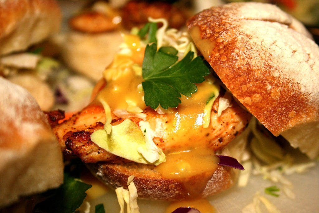A plate of chicken sliders with a sauce on them.
