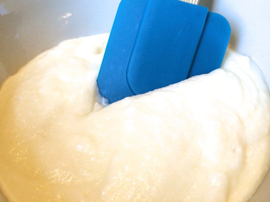 A blue spatula in a bowl of whipped cream.