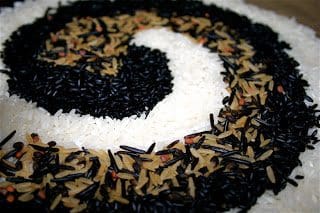 A spiral of black and white rice on a wooden table.