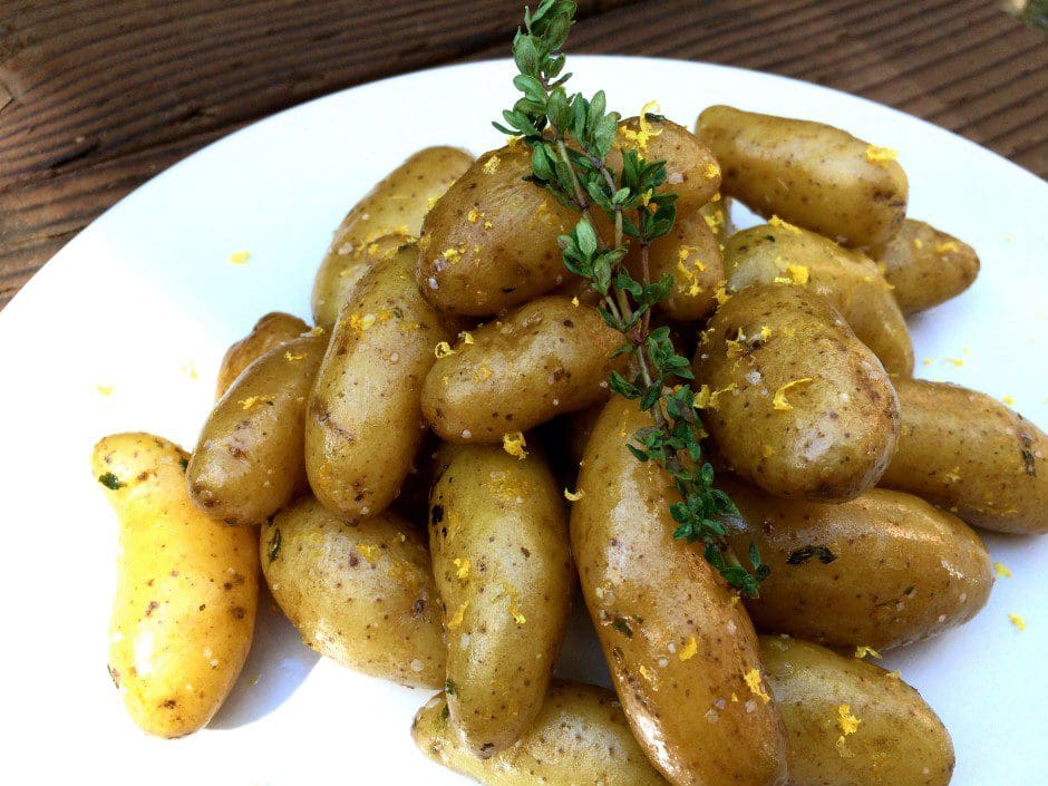 Roasted potatoes with thyme on a white plate.